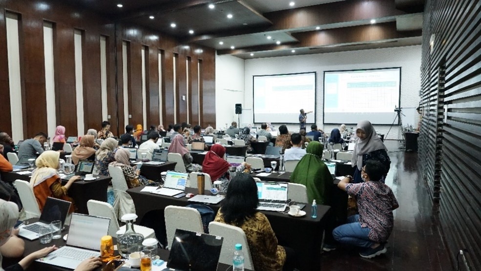 Participants of training in a meeting room, looking at the projector screen.